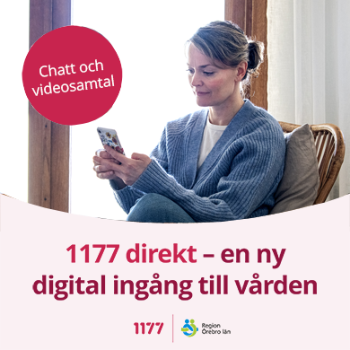 Kvinna sitter i fåtölj, i varma kläder och tittar i sin mobil. Hon ler. 