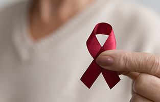 En hand som håller i symbolen för aids - ett rött band format som en ögla