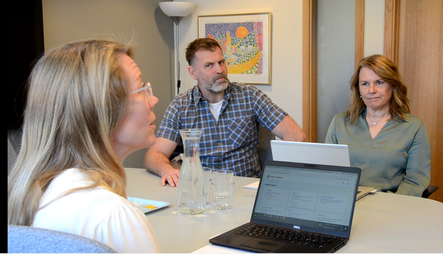 Tre personer sitter i möte kring ett bort